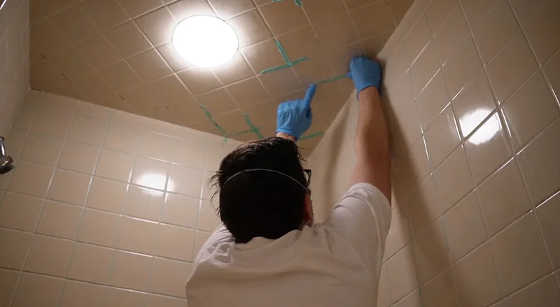 Technician cleaning a bathroom ceiling after mold treatment