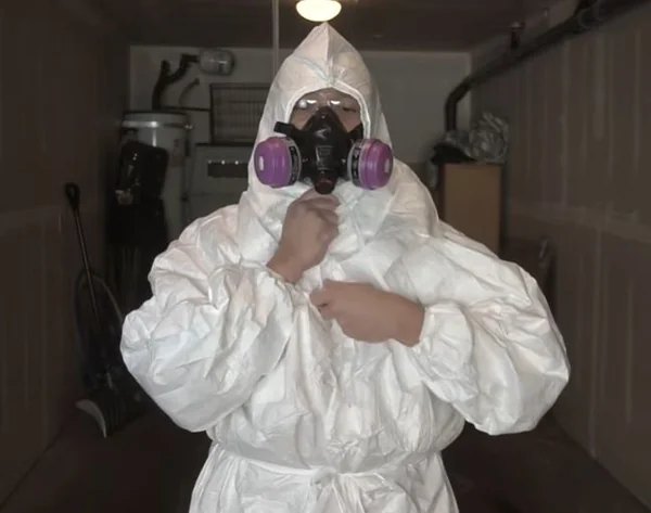 Mold removal specialist wearing a protective suit and full-face respirator